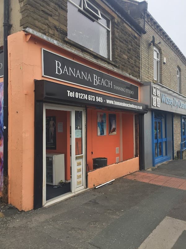 Banana Beach Tanning Studio storefront with orange facade, large sign, and nearby shops in Wibsey, Yorkshire.