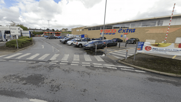 Pay & Display parking area near Tesco Extra in Wibsey, Yorkshire, with cars and a pedestrian crossing visible.