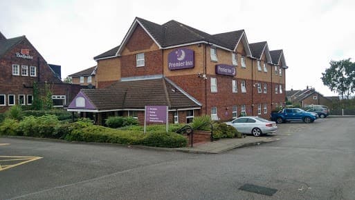 Premier Inn building with purple signage, surrounded by greenery and parked cars in Wickersley, Yorkshire.