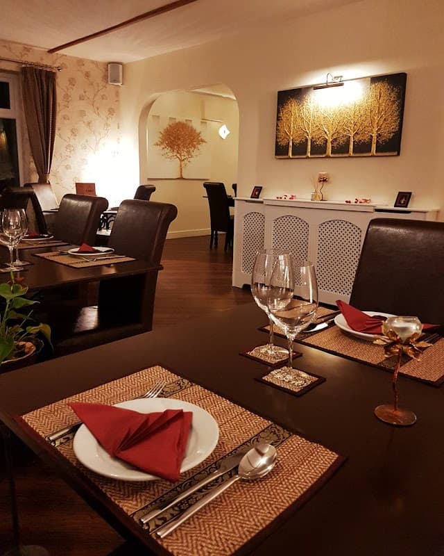 Elegant dining setup at Thai Season, featuring wooden tables, decorative trees on the wall, and neatly arranged tableware.