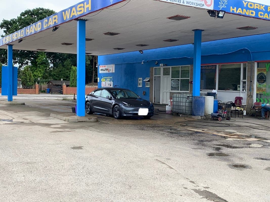 York Road Hand Car Wash with a black car parked in front, blue building, and various cleaning equipment visible.