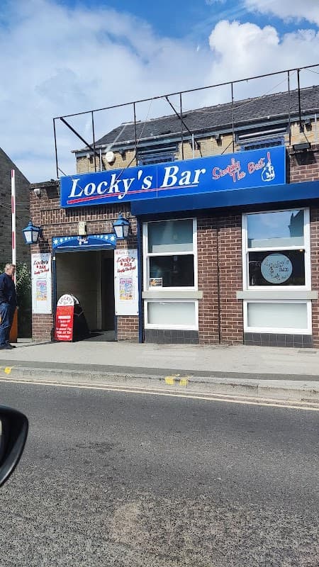 Exterior of Locky’s Bar featuring a blue sign, brick facade, and entrance with a red sign, set in Wombwell, Yorkshire.