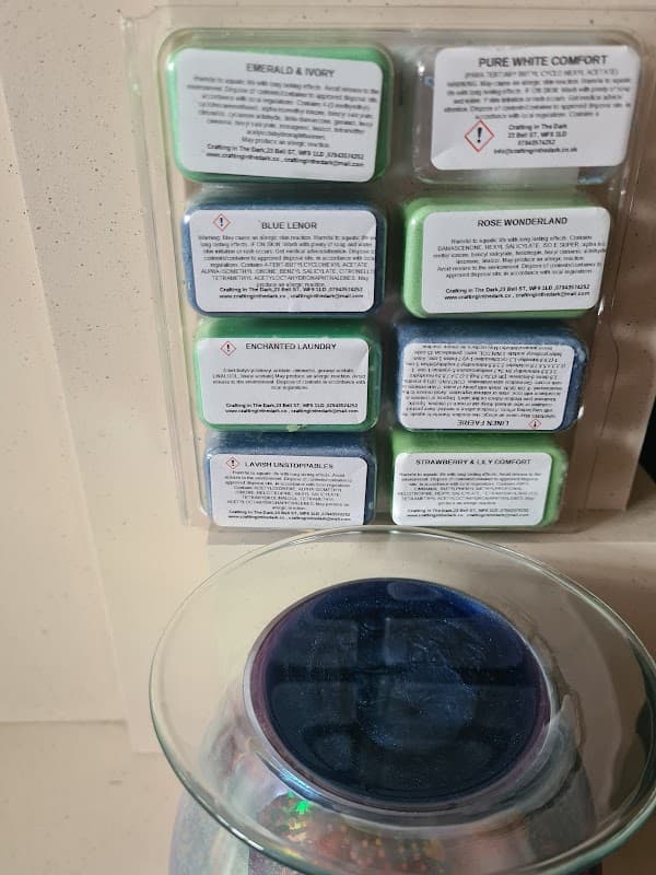 Wax melts in various colors and scents displayed on a wall, with a glass container below filled with colorful beads.