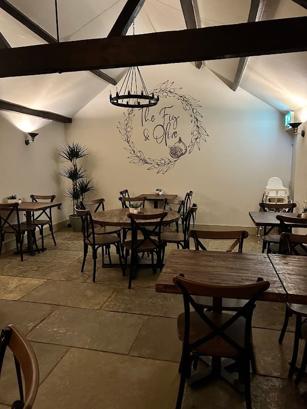 Cozy interior of The Fig & Olive with wooden tables, chairs, and a decorative wall mural in Womersley, Yorkshire.