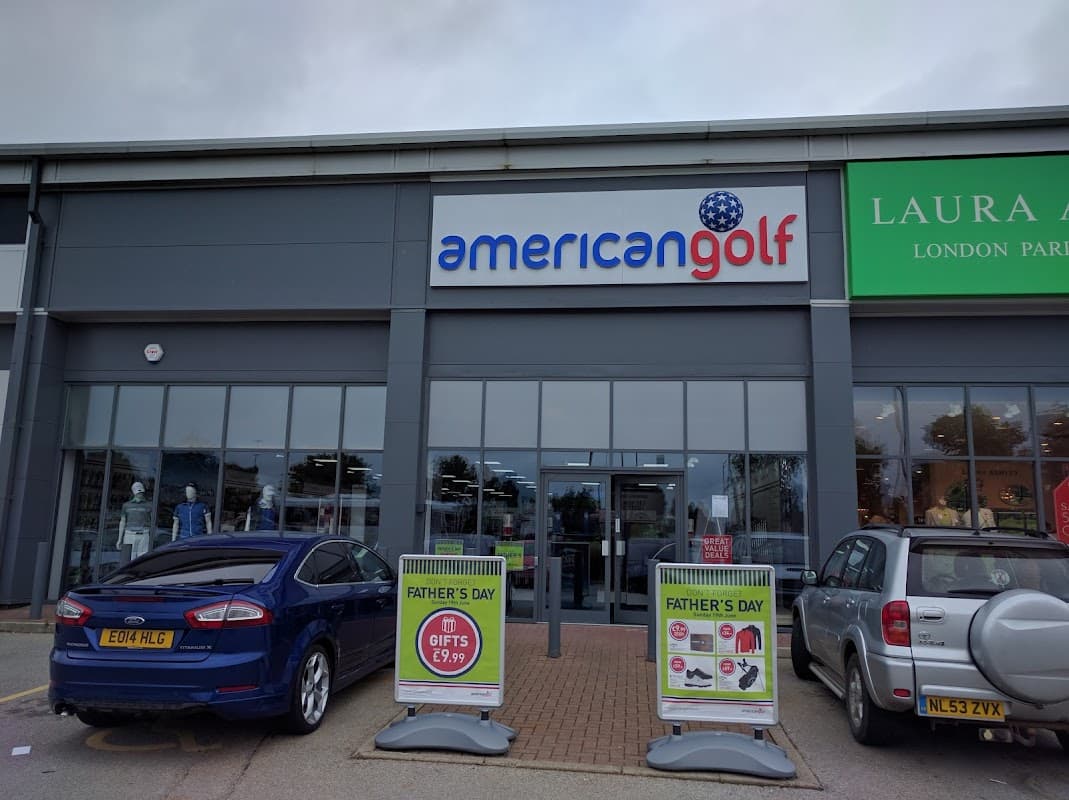 American Golf store front with signage, two parked cars, and promotional displays for Father's Day gifts.