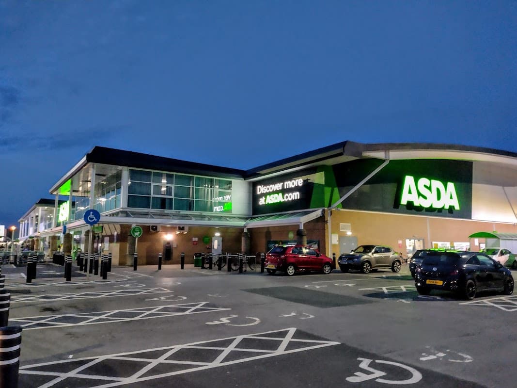 Asda York Superstore exterior at dusk, featuring a large sign, parking spaces, and cars in the lot.