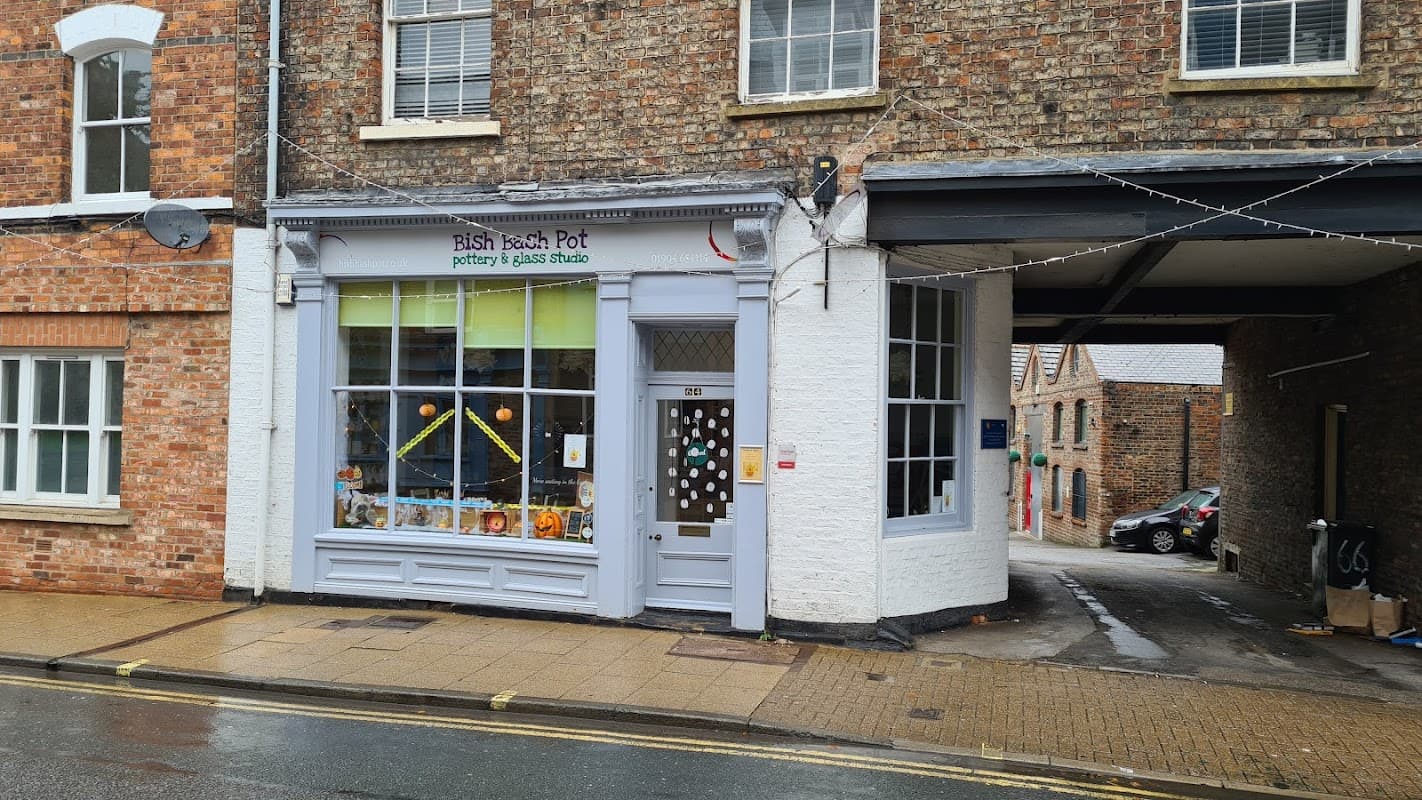 Colorful pottery shop with large windows, displaying art and craft items, located on a cobblestone street in York.