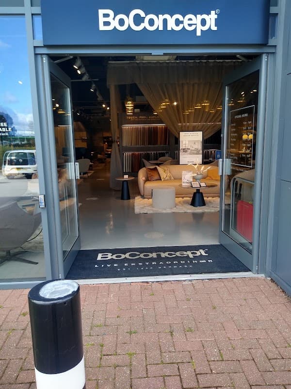 Entrance to BoConcept store with stylish furniture displays and a welcoming mat on the ground.