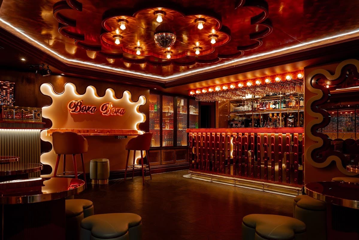 Vibrant nightclub interior with red lighting, stylish bar, and modern seating. Retro decor and a sparkling disco ball.