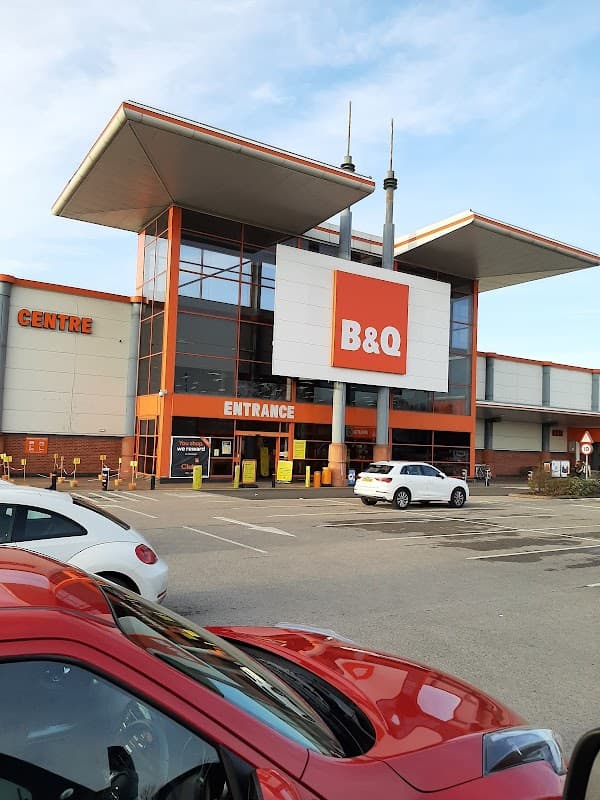B&Q store exterior with large entrance sign, modern architecture, and parked cars in front.
