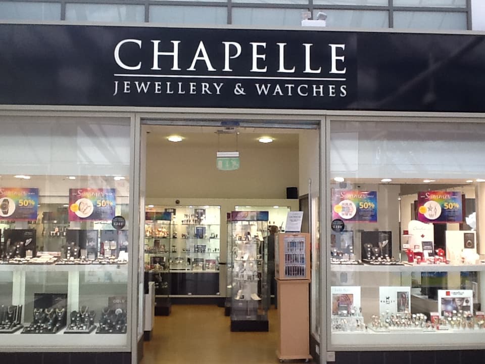 Storefront of Chapelle Jewellery with glass displays showcasing watches and jewelry, featuring sale signs.