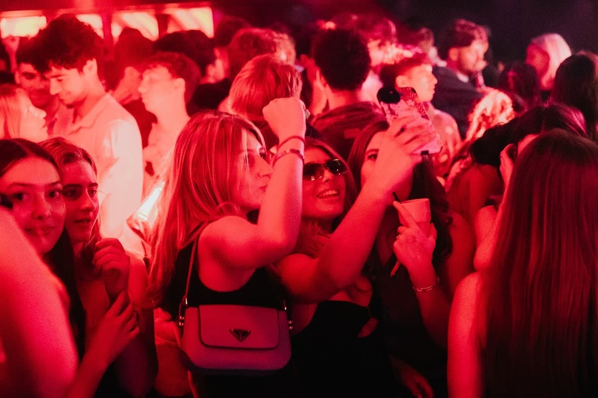 Crowd of young people enjoying themselves at CIRCUIT York nightclub, vibrant red lighting, taking selfies and dancing.