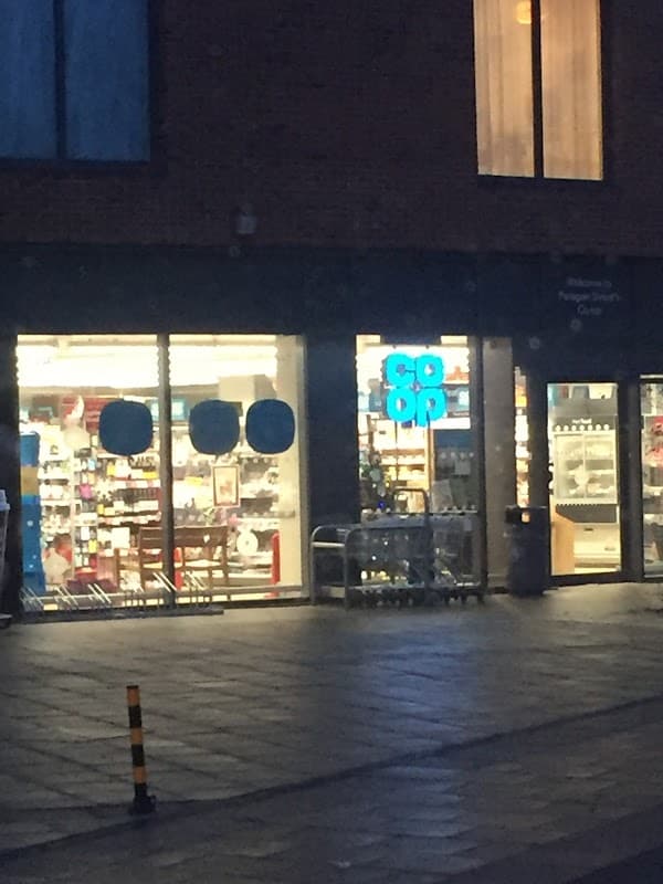 Co-op Food storefront on Paragon Street, illuminated at night, showcasing products through large glass windows.