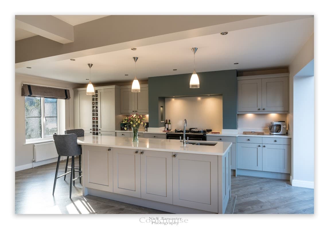 Modern kitchen with gray cabinetry, white countertops, pendant lighting, and a central island with bar stools.
