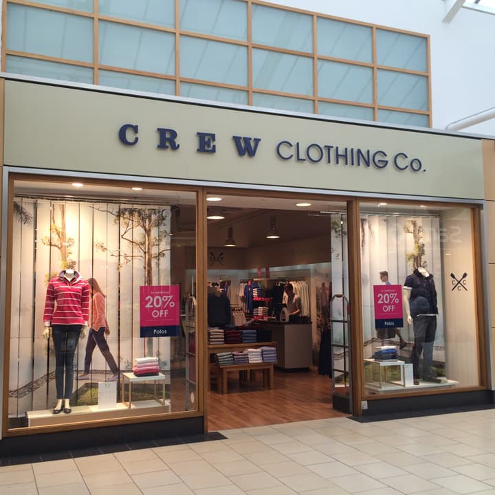 Crew Clothing Company outlet with mannequins in stylish clothing, promotional signs for 20% off, and a bright interior.