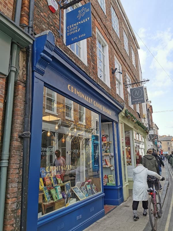 "Exterior of 'Criminally Good Books' shop in York, featuring colorful book displays and a charming brick facade."