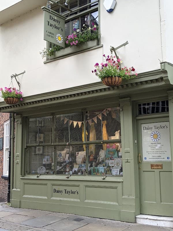 Charming gift shop with green facade, flower baskets, and a display of cards and gifts in York, Yorkshire.