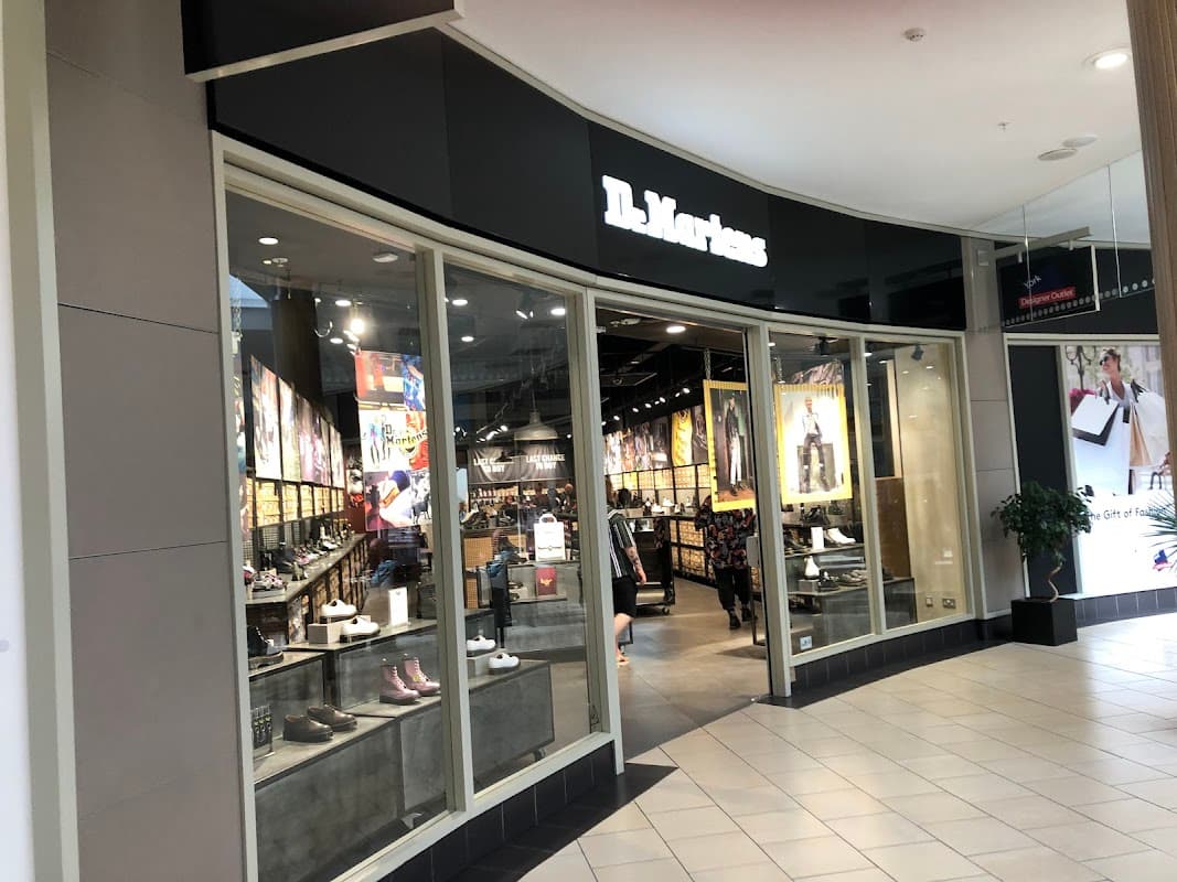 Entrance of Dr. Martens shoe shop featuring large windows, displays of footwear, and vibrant wall art.