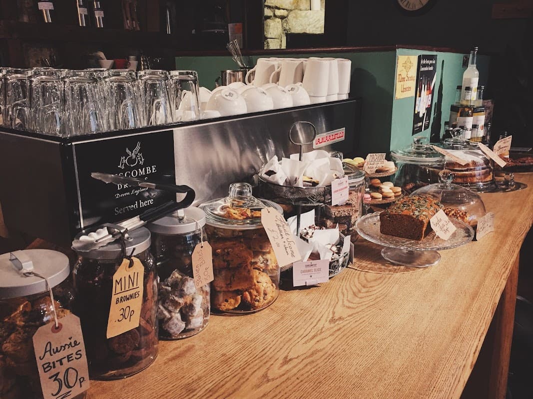 Glass jars filled with baked goods, a wooden counter, and a coffee machine in a cozy cafe setting.