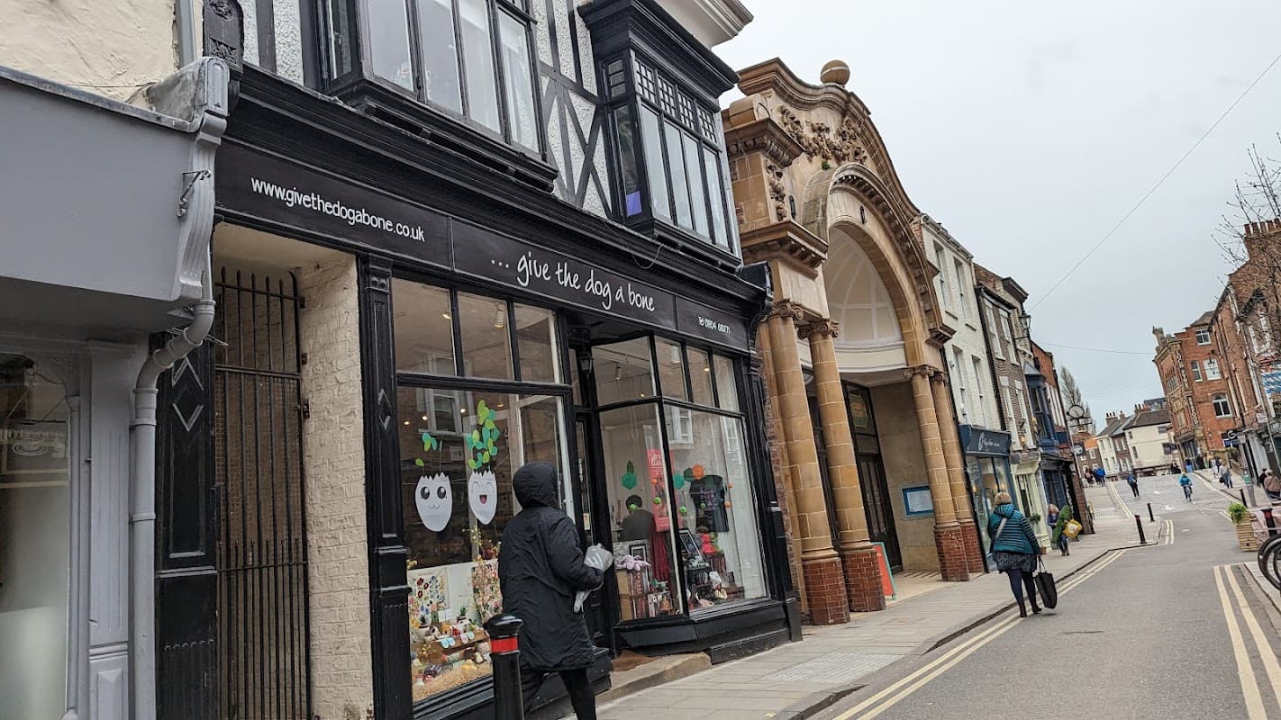 Charming gift shop with a black sign, festive decorations, and a pedestrian walking by on a quaint York street.