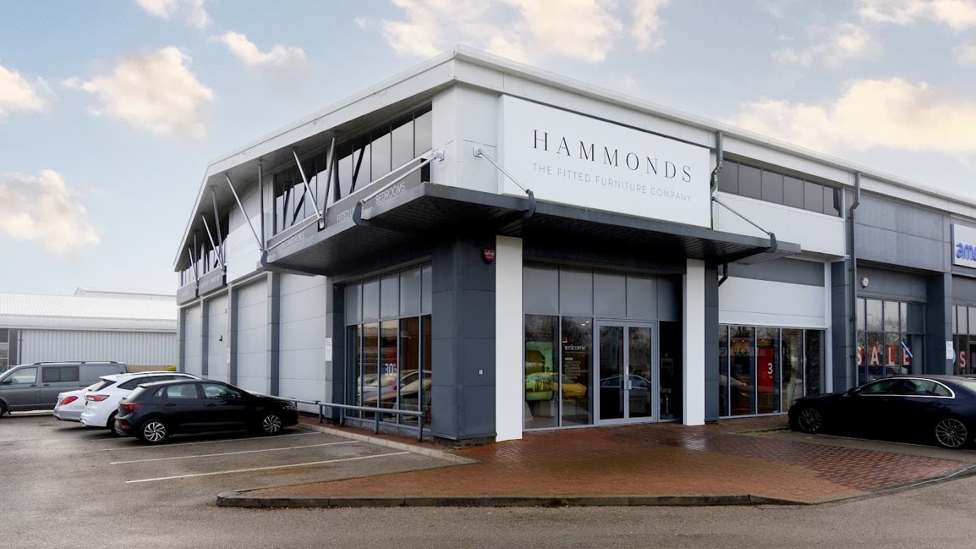 Modern furniture shop exterior with large glass windows, "Hammonds" signage, and parked cars in front.