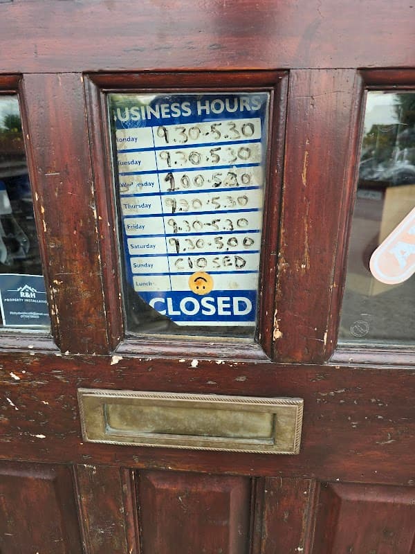 Business hours sign on a wooden door, showing opening times and a "CLOSED" notice.