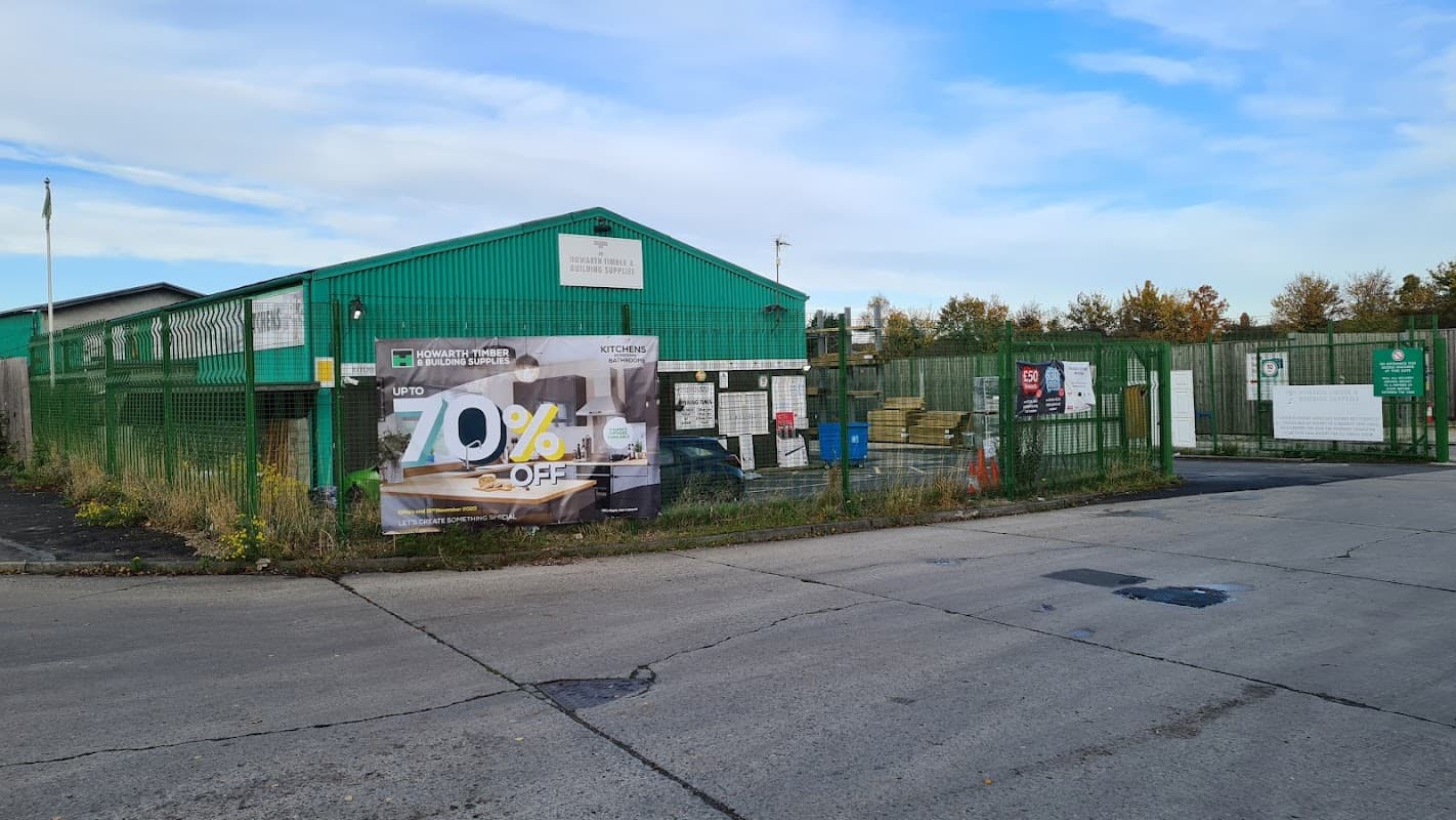 Green warehouse with a large sale banner, surrounded by a fence, and a clear blue sky above.