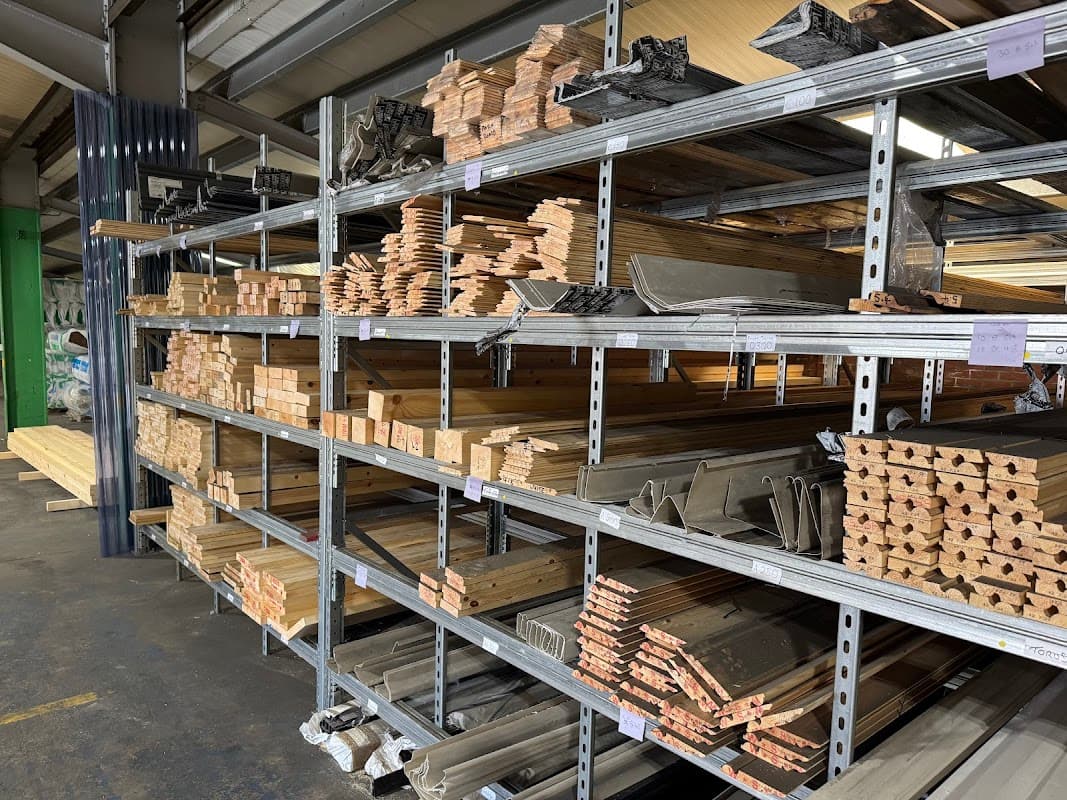 Shelves stocked with various wooden planks, metal sheets, and building materials in a hardware store.