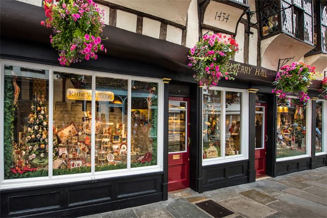 Charming gift shop with festive window displays, colorful flower baskets, and traditional architecture in York, Yorkshire.