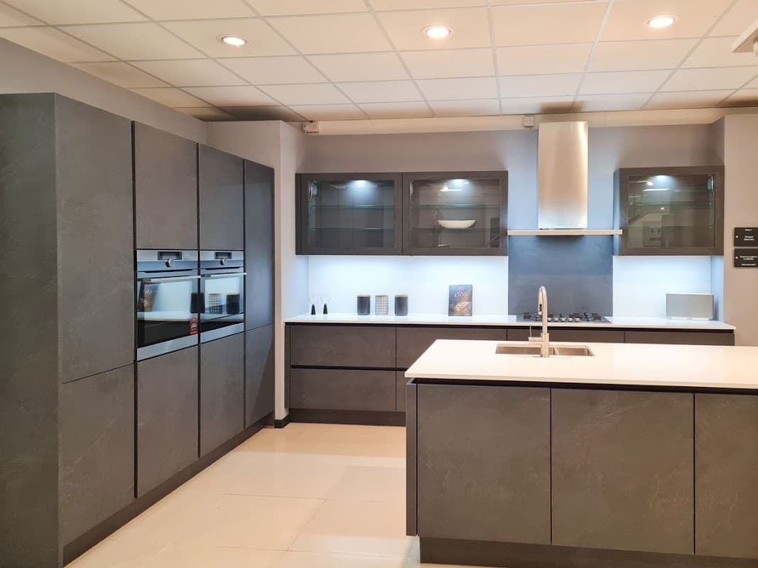 Modern kitchen display featuring sleek gray cabinetry, stainless steel appliances, and a minimalist island with a sink.