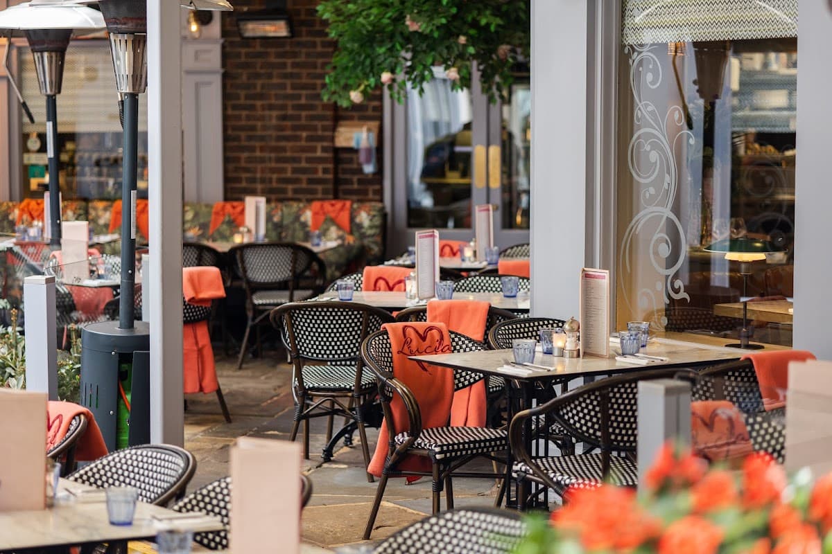 Outdoor dining area with black wicker chairs, tables set with menus, and vibrant greenery in York, Yorkshire.
