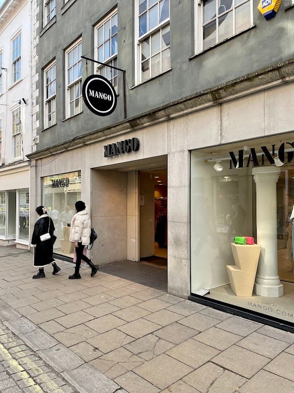 MANGO clothing store entrance in York, with shoppers and large windows displaying merchandise.