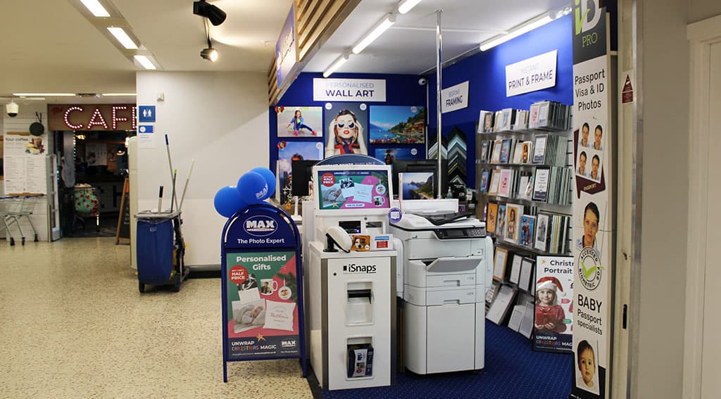 Bright store interior featuring personalized wall art, photo printing services, and various framed photos.