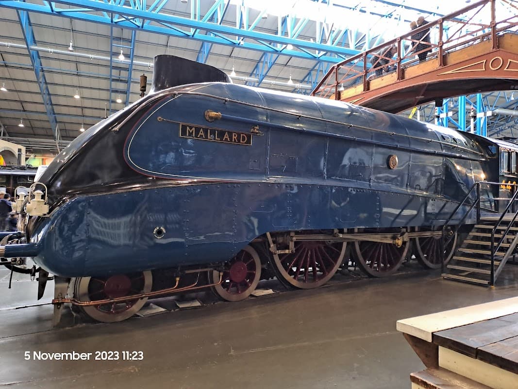 Steam locomotive Mallard, a blue train with large wheels, displayed indoors at the National Railway Museum in York.