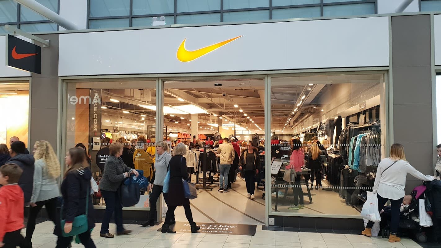 Nike Factory Store entrance with shoppers browsing athletic apparel and footwear in a busy retail environment.