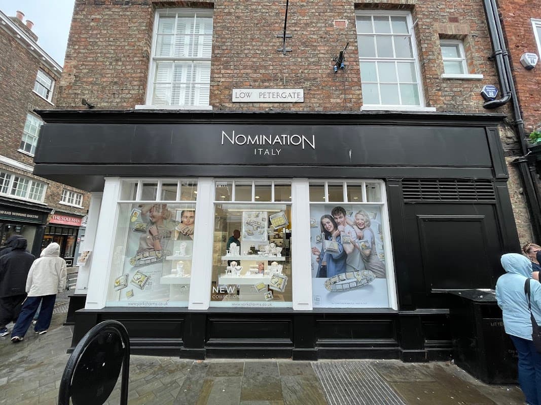 Jewellery store "Nomination Italy" with large windows displaying products, located on a cobblestone street.