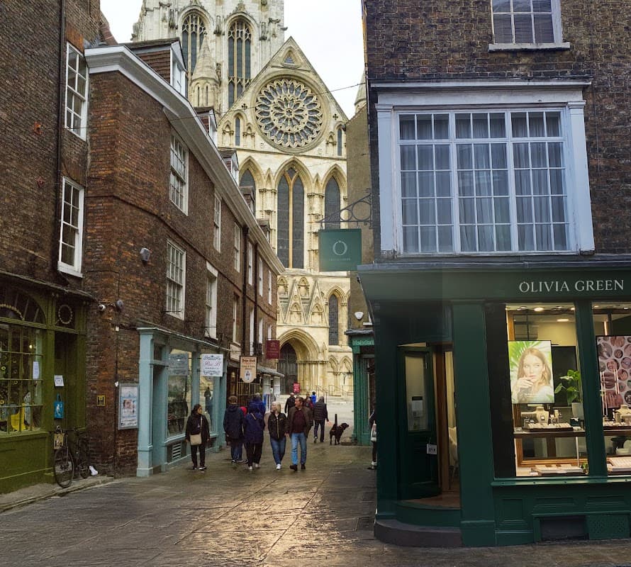 Olivia Green jewellers storefront with large windows, people walking, and York Minster in the background.