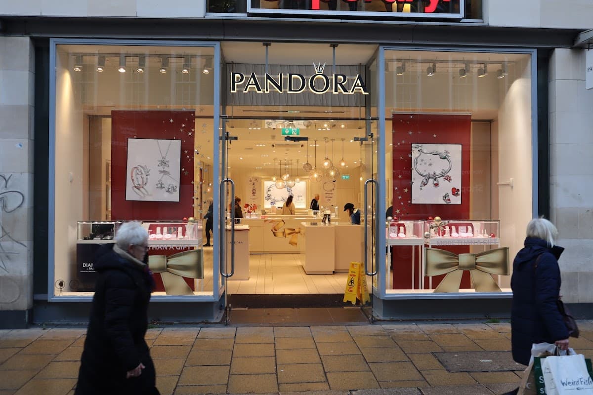 Jewellery store with large glass windows, featuring displays of necklaces and charms, and a festive red and gold theme.