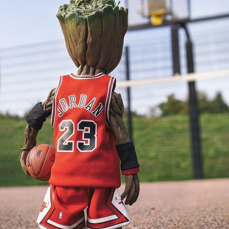 A small figure resembling a tree, wearing a red basketball jersey with "JORDAN 23," holding a basketball on a court.