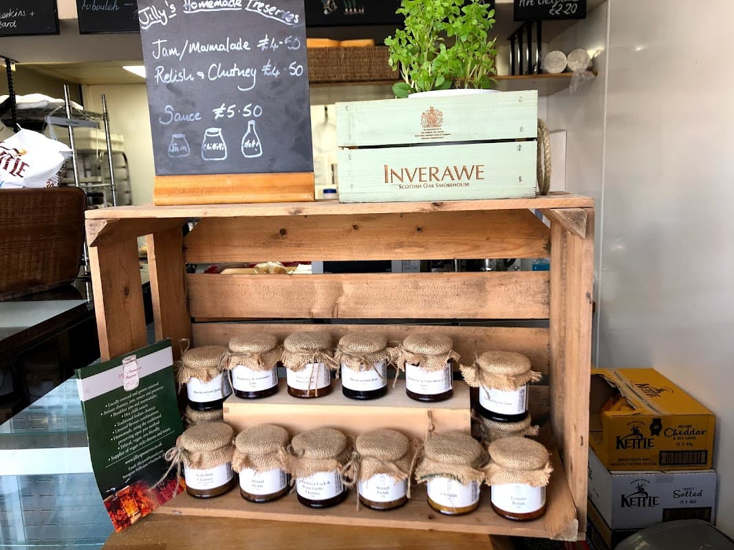 Wooden display with jars of jam and chutney, a potted herb, and a chalkboard menu at Pattacakes bakery.