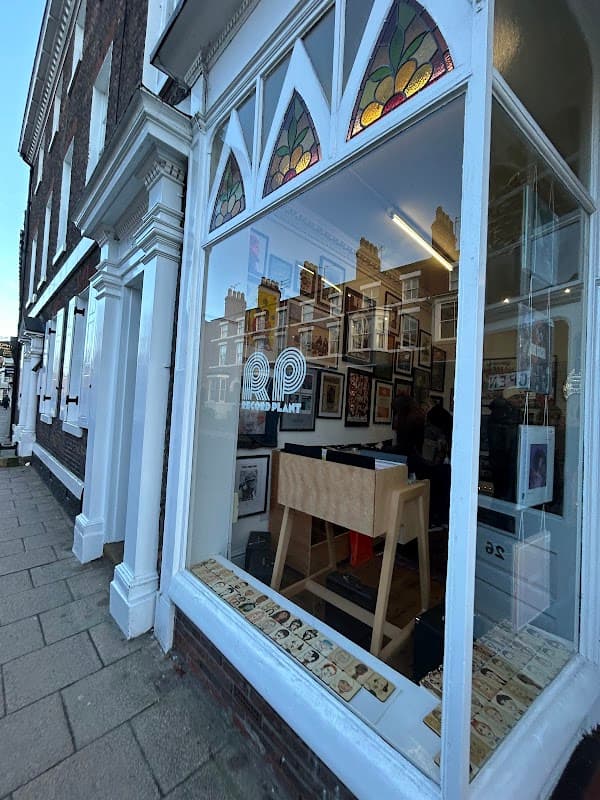 Storefront of Record Plant York featuring a display window with framed pictures and a wooden display stand.