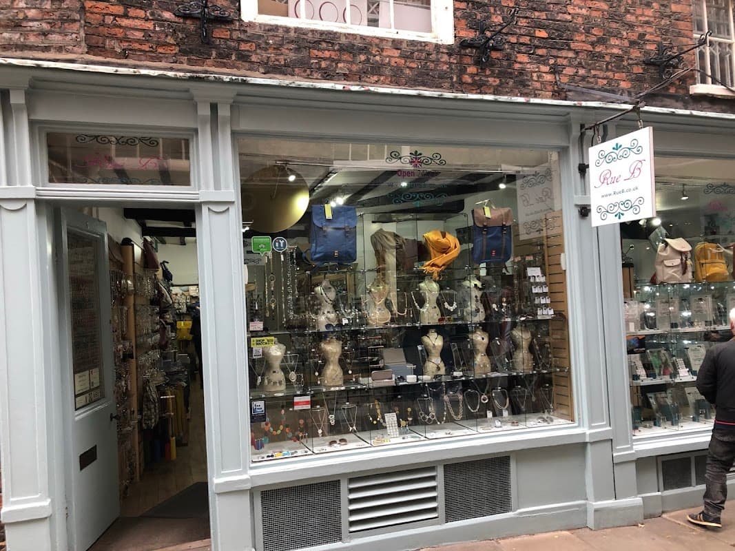 Jewellery shop window displaying necklaces, earrings, and accessories, with a sign reading "Rue B" above.
