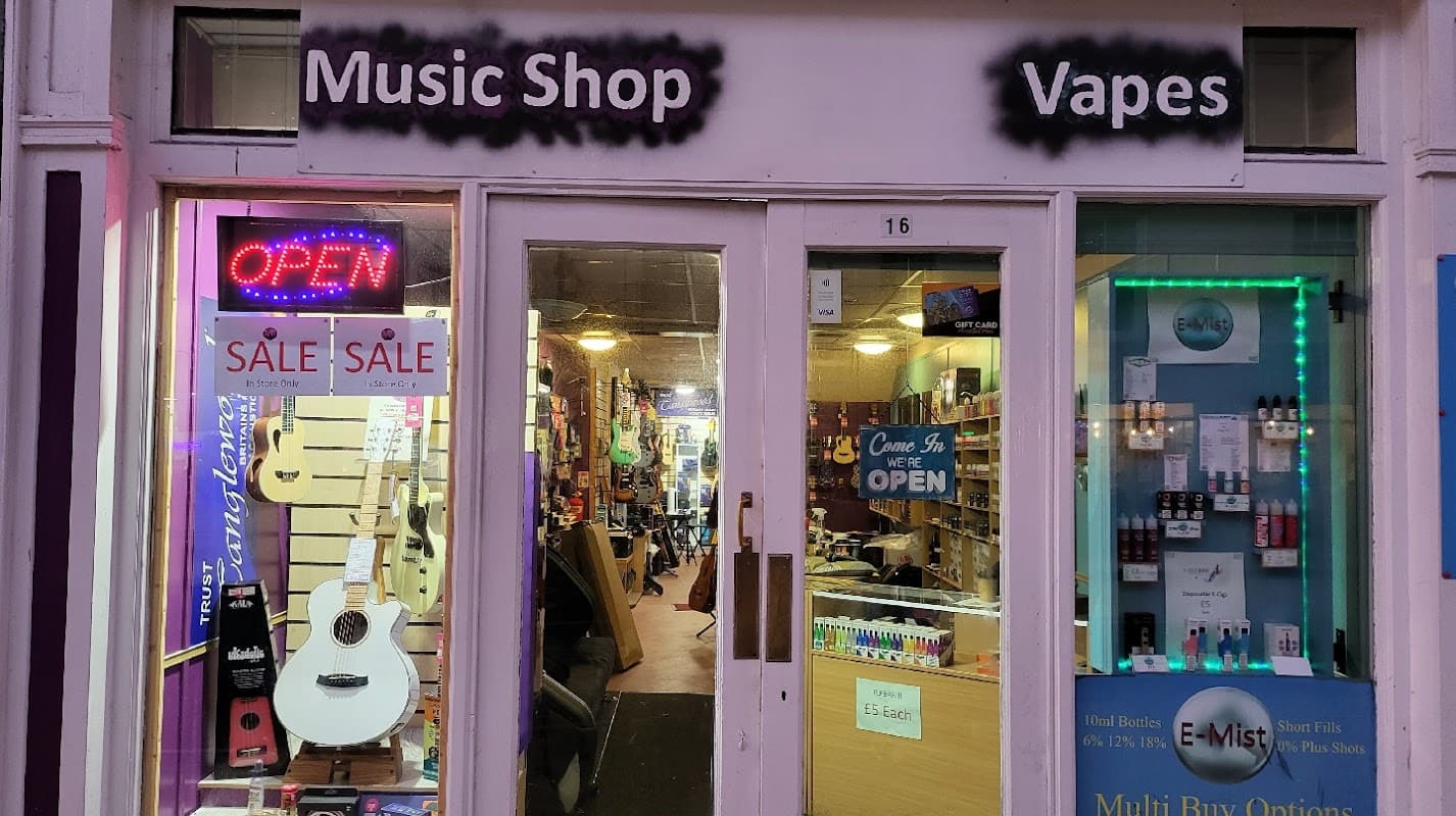 Music shop storefront with guitars, an "OPEN" sign, and vape products displayed in the window.