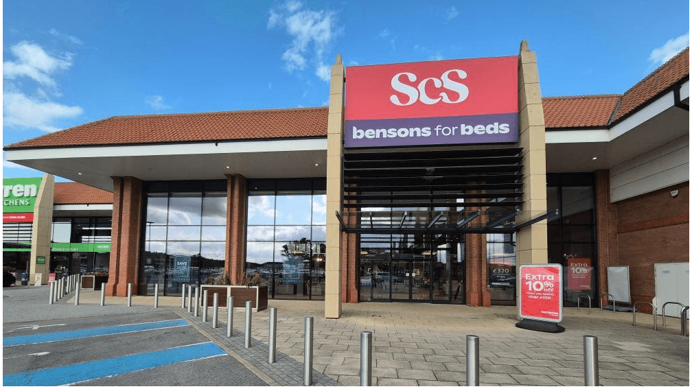 ScS York store entrance with large windows, red signage, and promotional banners outside.