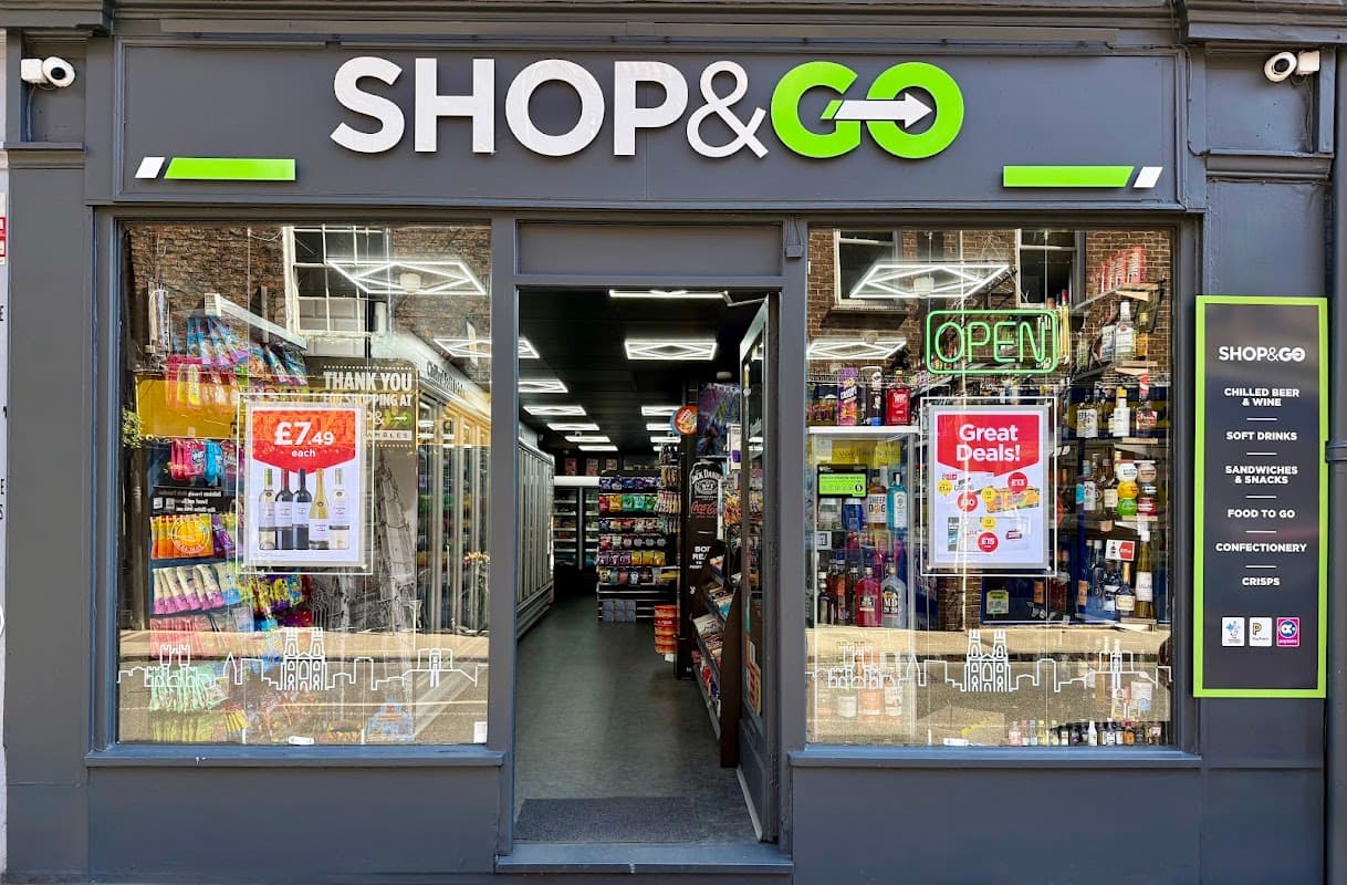 Bright storefront of SHOP & GO with open sign, displaying drinks, snacks, and promotional posters in York.
