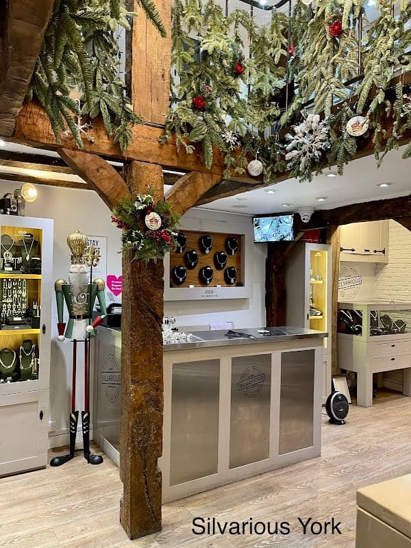 Handmade silver jewellery display in a charming shop with wooden beams and festive decorations.
