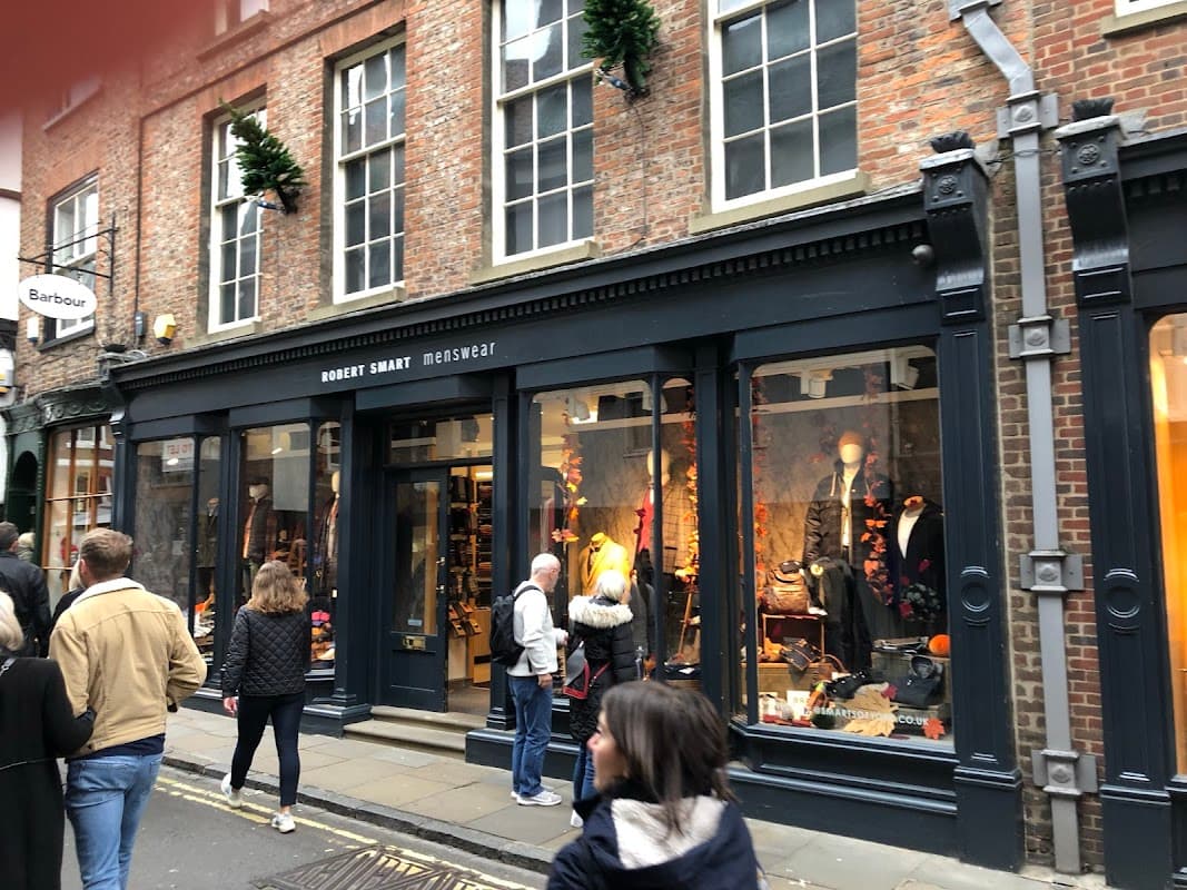 Front of Robert Smart Menswear shop with stylish clothing displays and shoppers on a bustling street in York.