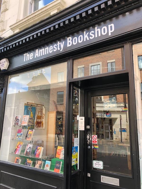 The Amnesty Bookshop features a black storefront with large windows displaying colorful books and a welcoming entrance.