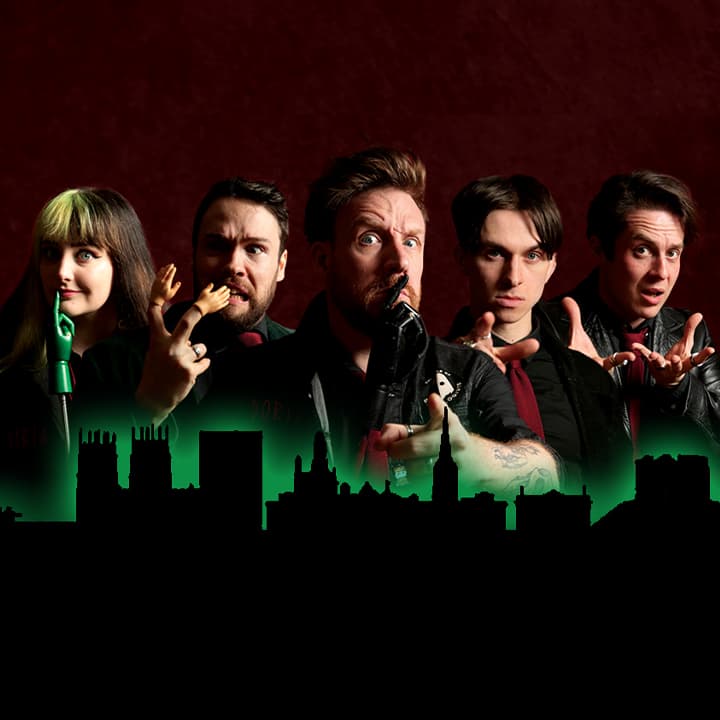 Five performers in dark attire pose dramatically against a shadowy city skyline, evoking a spooky atmosphere.