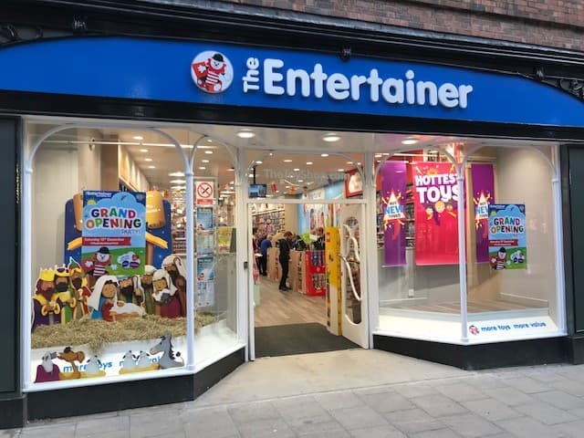 Bright storefront of The Entertainer toy shop in York, featuring colorful displays and a grand opening sign.